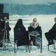 Anya Chalotra, Freya Allan, and Henry Cavill on location filming The Witcher season 3, sitting in chairs as they look across a snowy plane with a horse in the distance.